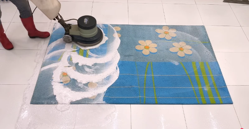 Carpet cleaning technician scrubbing an area rug with a rotary machine
